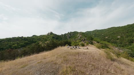 Dynamic-FPV-drone-shot,-parallax-movement,-showing-a-young-man-sitting-on-a-vista-point-in-Dürnstein,-enjoying-the-view,-revealing-ruin-dürnstein-in-the-background