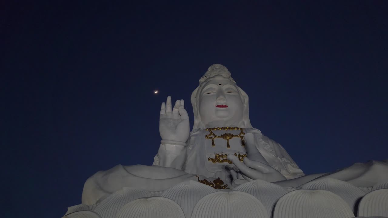 dolly en mcu: gran buda blanco brilla bajo el cielo nocturno iluminado por la luna