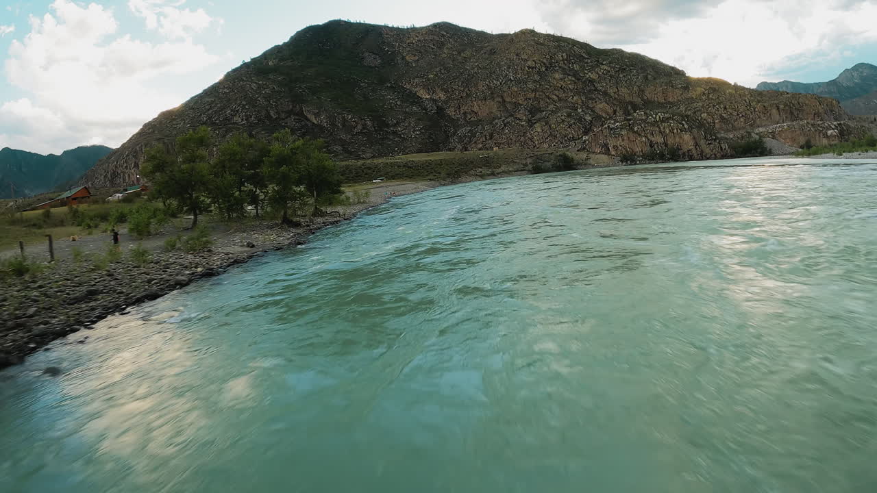 olas de río de montaña azul primer plano. corriente de agua áspera corre a través del valle de las tierras altas contra acantilados rocosos fpv dron. flujo de salpicaduras en el lecho del río