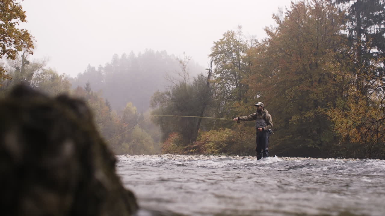 Man fly fishing in a misty autumn river