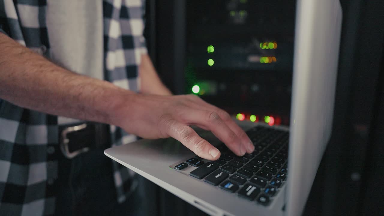 Technician working on a laptop in a server room