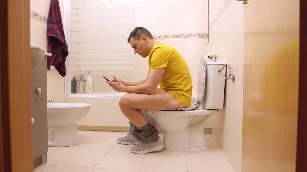Man using smartphone on toilet, getting interrupted and closing door