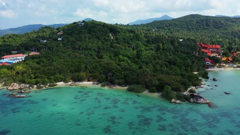 holiday resorts on coastline of tropical island with trees forest, secret beaches and cliffs, turquoise sea in koh phangan, thailand