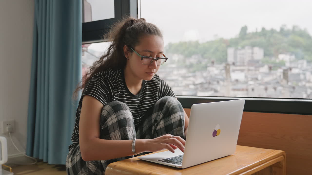 Workspace for writing. Desk with laptop and city view. Writing station overlooking urban skyline with focus. Creative workspace featuring manuscripts and city lights outside window