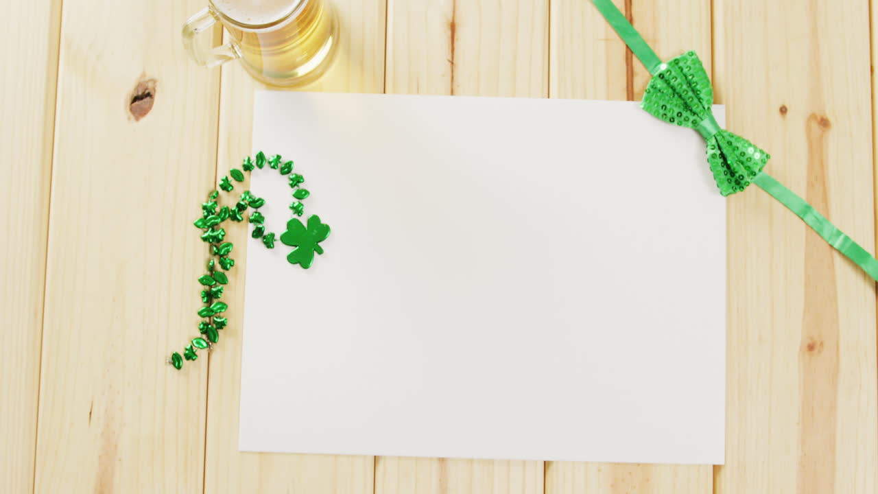 Video of st patrick's green shamrock and white paper with copy space on wooden background