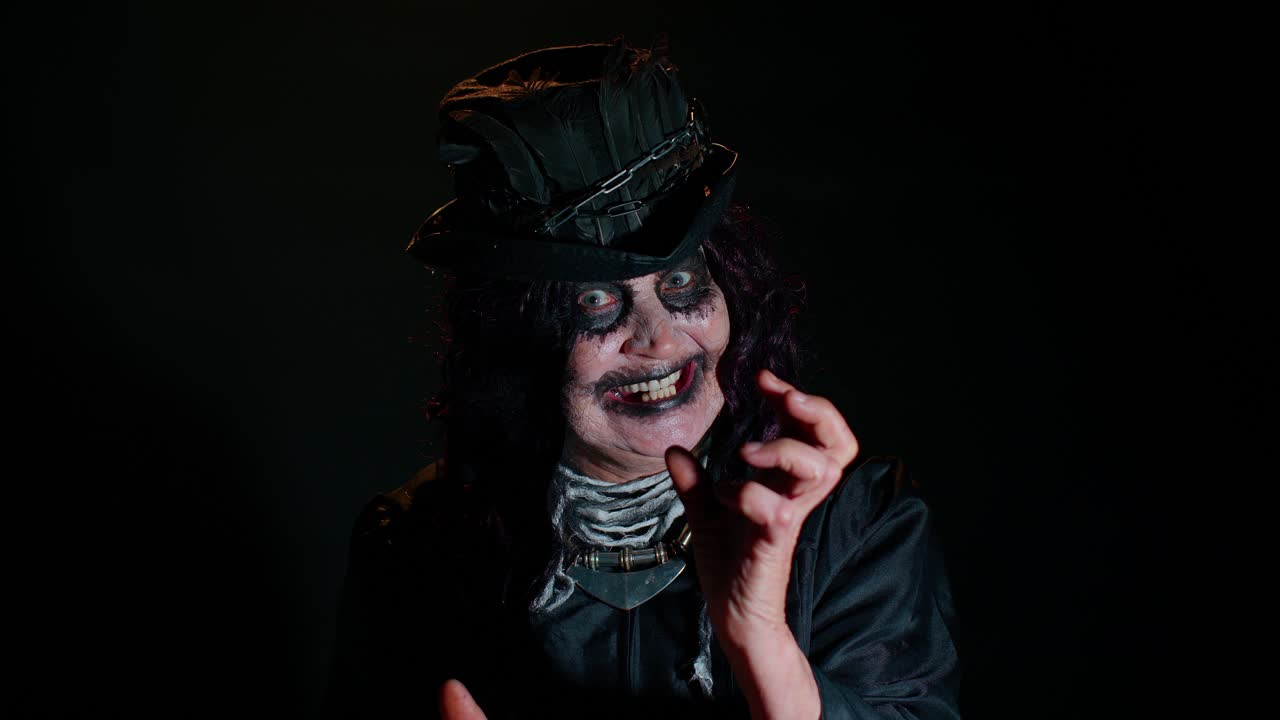 mujer madura y siniestra en disfraz de carnaval de bruja de halloween haciendo caras, tratando de asustar