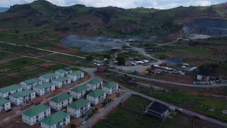 drone video capturing expansive view of an estate housing construction site nestled in rocky, rural landscape under a cloudy sky in abuja. scene conveys a sense of development amidst nature in africa