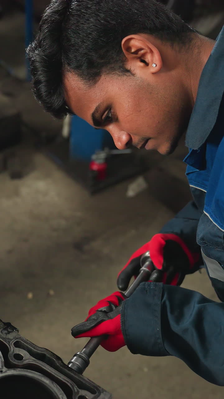 primer plano de un ingeniero automotriz soltando una nuez en el bloque del motor con guantes rojos, centrado en la precisión en el taller automotriz, con un observador con guantes blancos de pie cerca