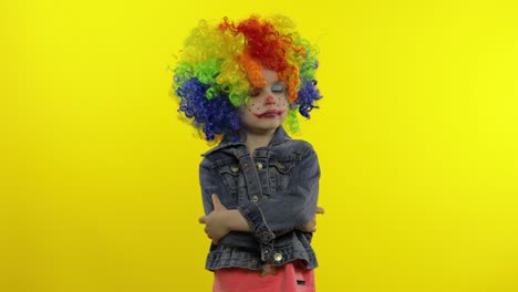 una niña payasa con una peluca colorida haciendo caras tontas. tonto, sonriendo, bailando. halloween