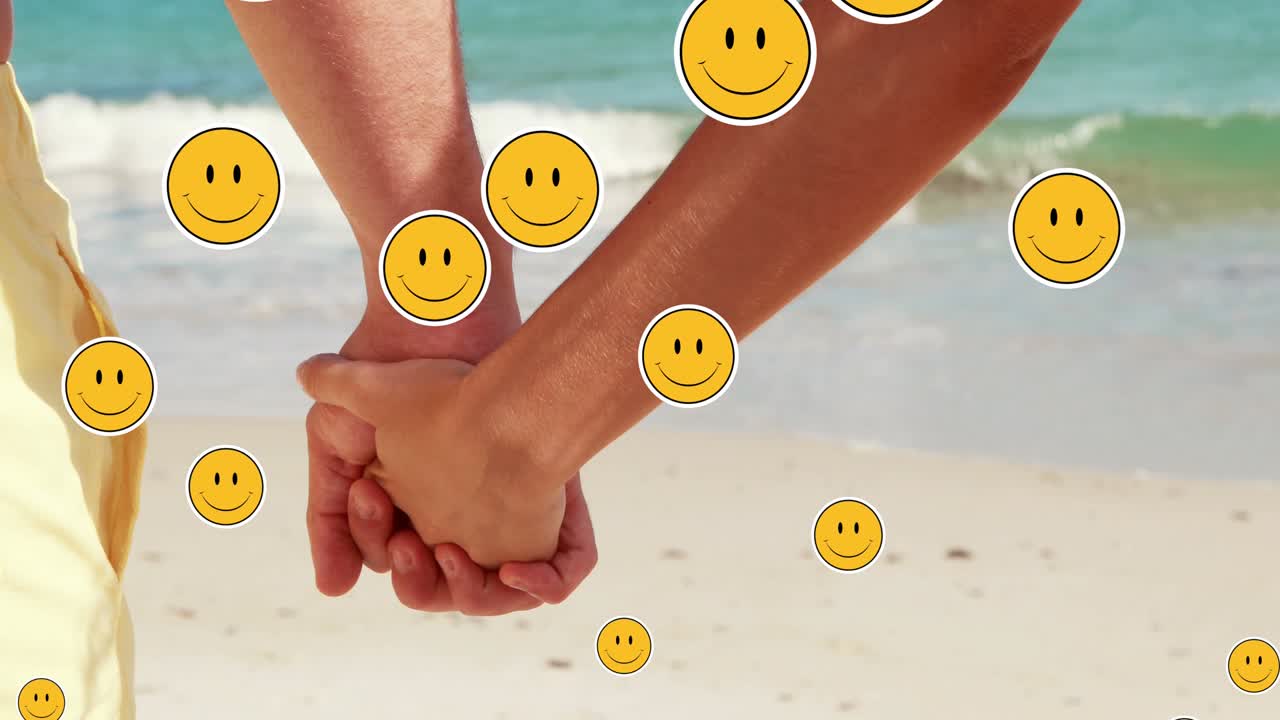 несколько улыбающихся лиц эмодзи, плавающих на середине секции пары, держащейся за руки на пляже