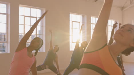 yoga class of young healthy people practicing reverse warrior pose instructor woman teaching diverse group enjoying fitness lifestyle exercising in studio at sunrise