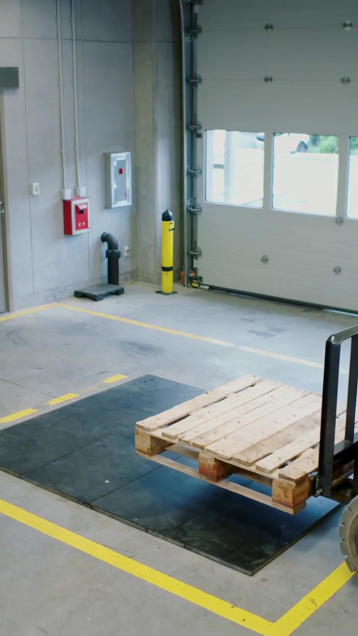Vertical video: Entering forklift carrying pallet into bay, placing onto mat to weigh, copy space
