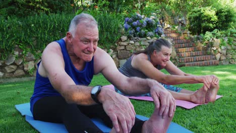 pareja de ancianos caucásicos realizando ejercicios de estiramiento juntos en el jardín