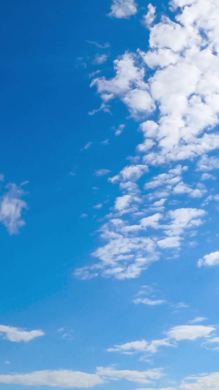 Quick transformation of white soft clouds in the atmosphere. Cumulus cloudscape moving with the wind from low angle perspective. Timelapse. Vertical video