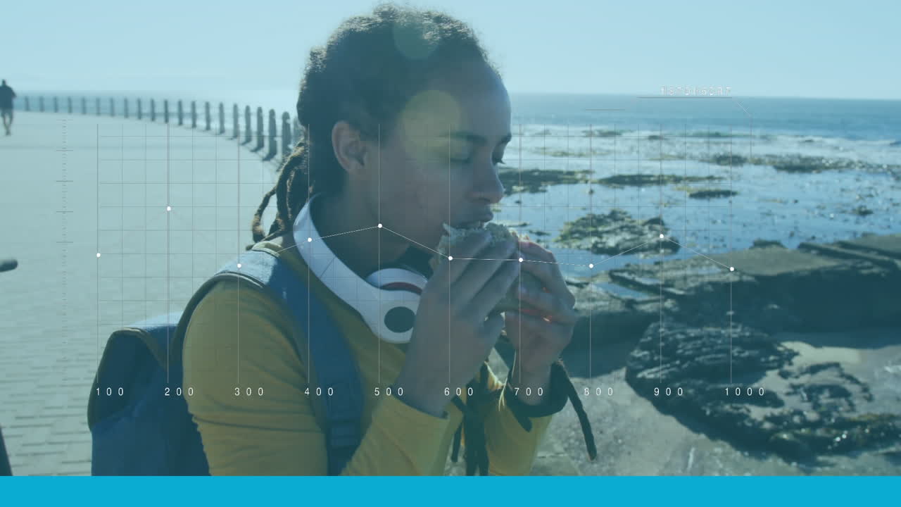 procesamiento de datos estadísticos contra una mujer afroamericana que come un bocadillo en el paseo marítimo