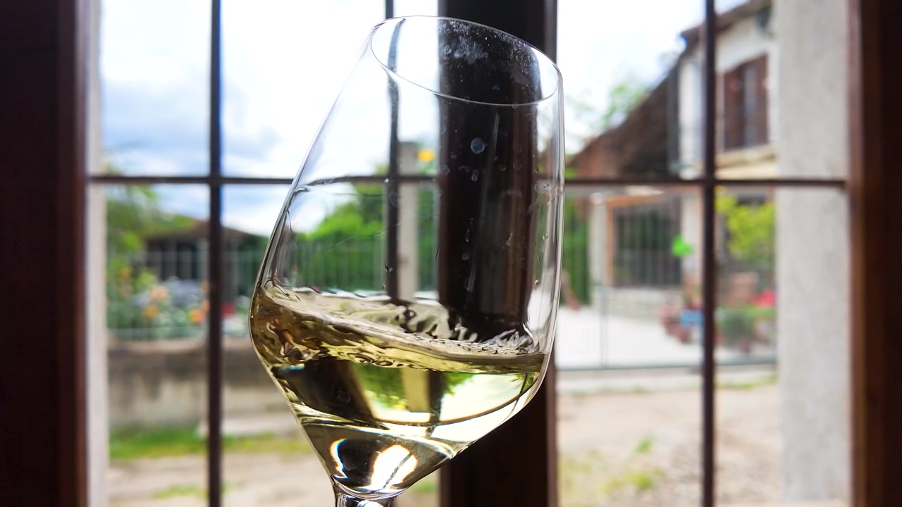 Un primo piano statico di vino bianco che volteggia in un bicchiere in una cantina vinicola italiana