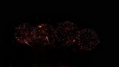 coloridos fuegos artificiales reales celebran la víspera de año nuevo con un desenfoque abstracto de brillo dorado con luces bokeh en el cielo nocturno