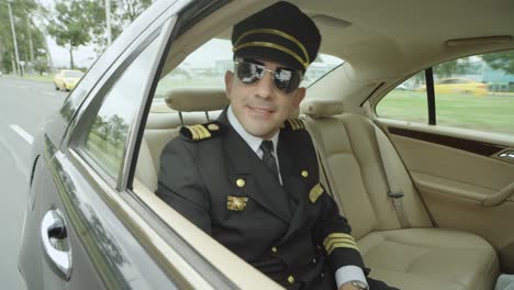 a pilot use glasses sits in a seat inside a black car that drives him