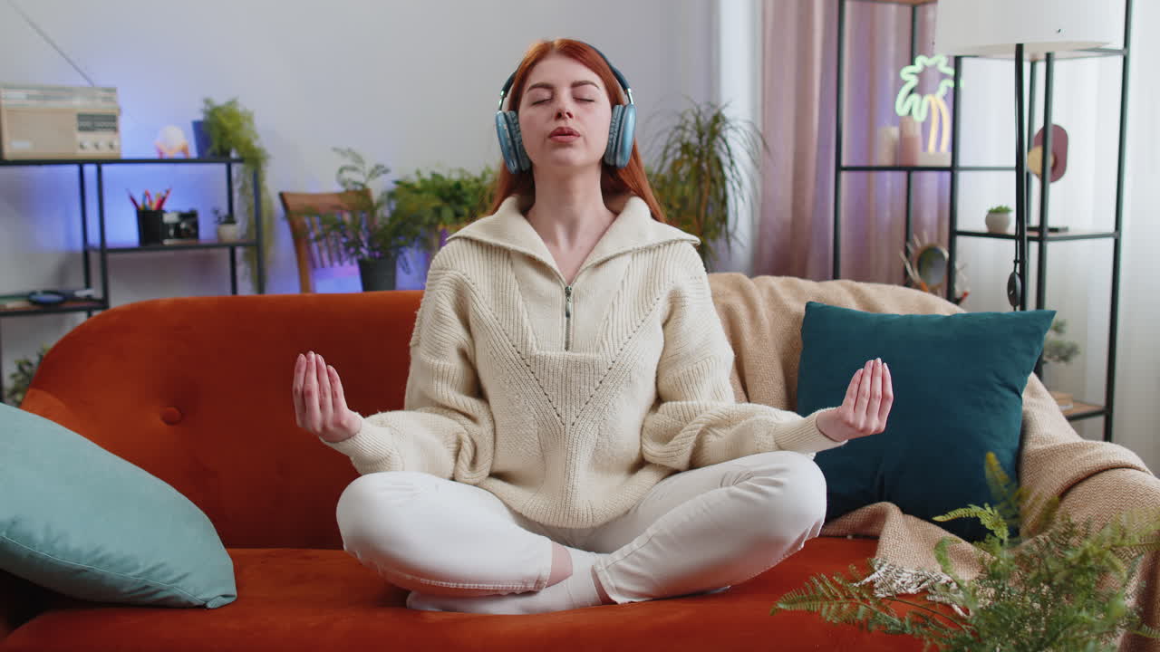 Woman breathes deeply eyes closed meditating with concentrated thoughts peaceful mind at home