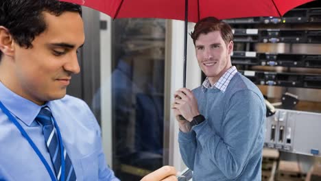 animation of caucasian man with umbrella over biracial male worker inspecting server room