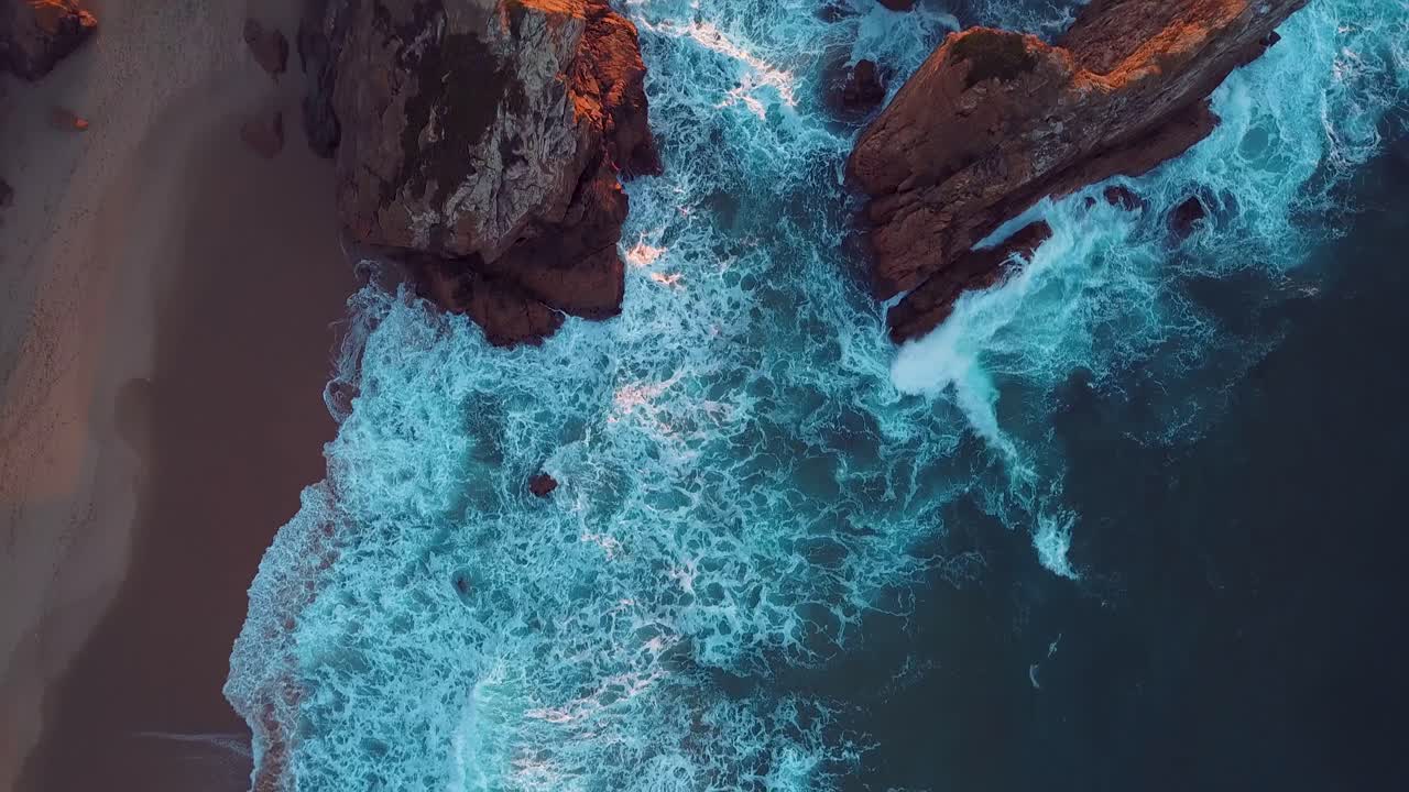 Waves seen from above from Ursa Beach in Sintra, Portugal. Shot during sunset in the summer. View straight down to the crashing waves.
