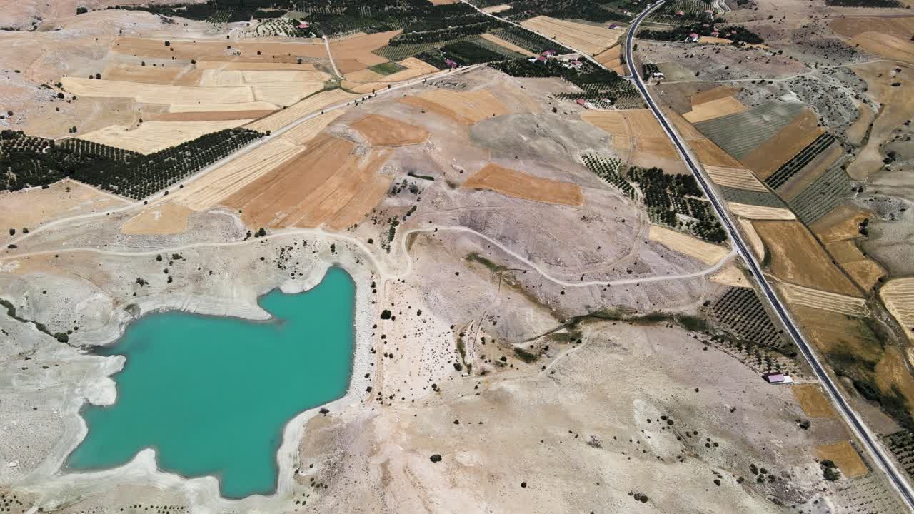 Drone filming of a small lake lost between hills and fields near a road in Turkey