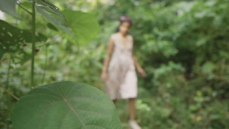 young woman walks in a lush forest, with mixed focus and blur effects, creating a dreamy atmosphere