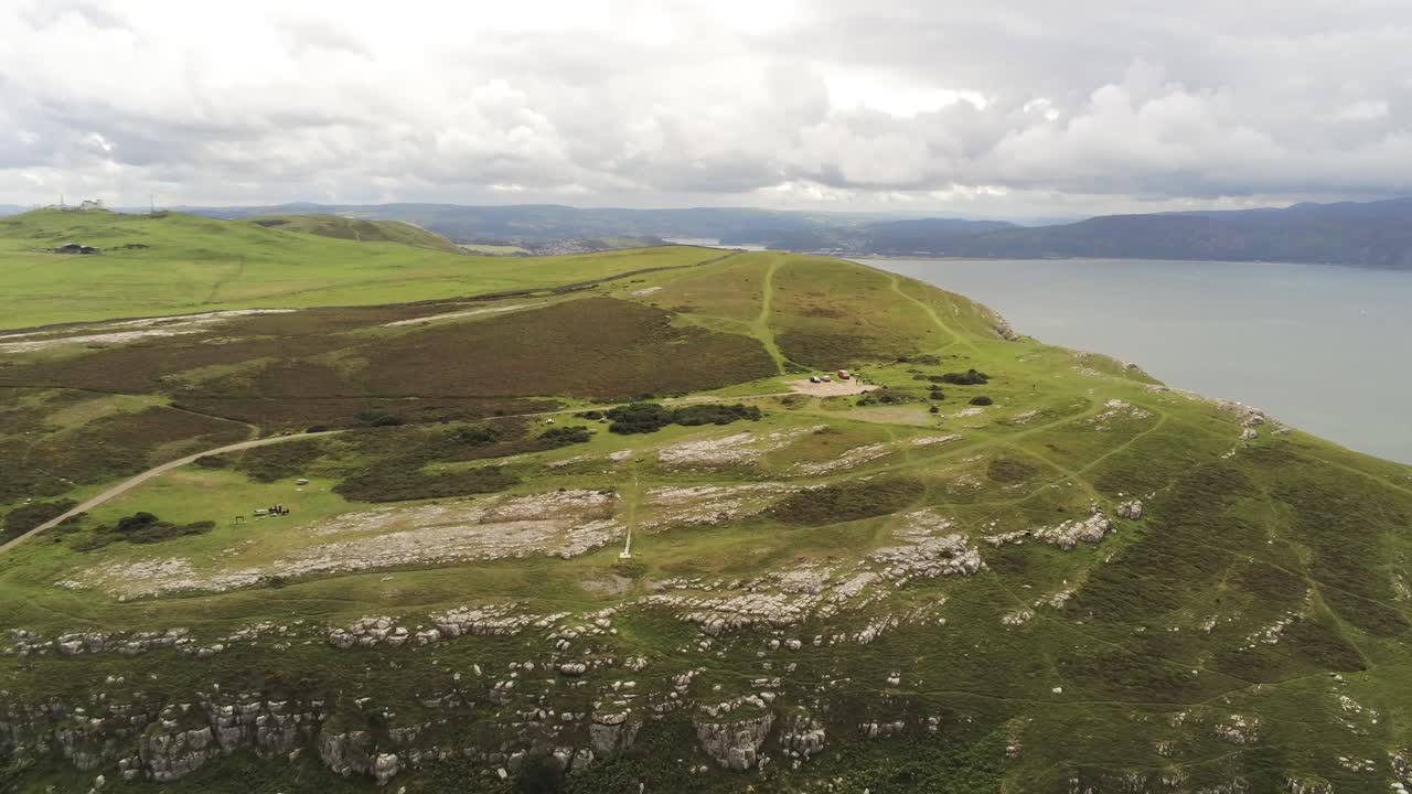 Luftfoto stiger op over Great Orme Llandudno bjergdal landskab trækker tilbage