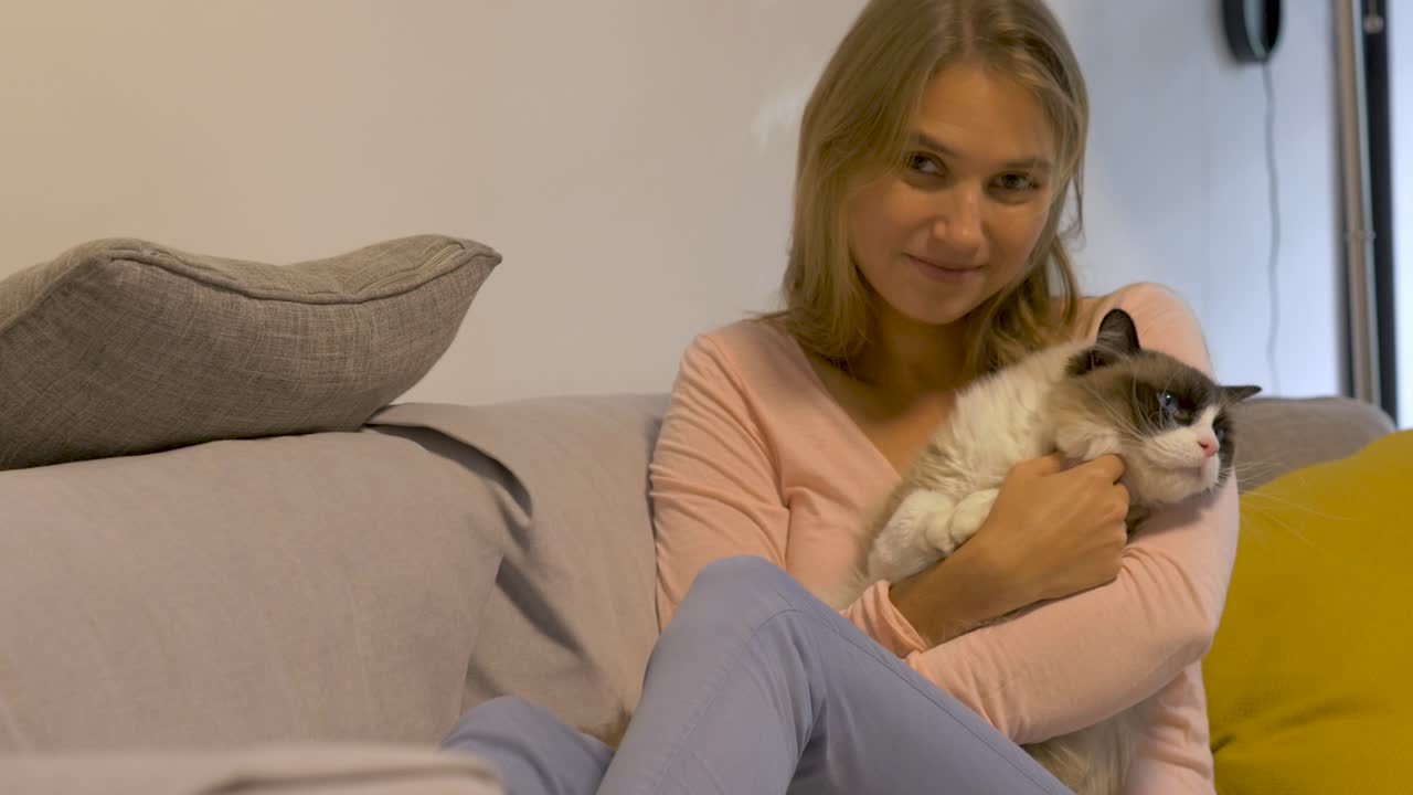 그녀의 손에 카메라 문신 미소 좋은 새끼 고양이와 함께 소파에 앉아 예쁜 여자