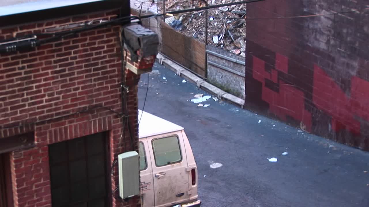 이 내부 장면에서 카메라는 오래된 아파트 건물 주변에 쌓이는 쓰레기를 보기 위해 옥상 위로 패닝합니다.