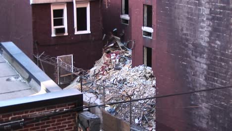 in this innerscene the camera pans up and over a rooftop to view trash piling up around an old apartment building