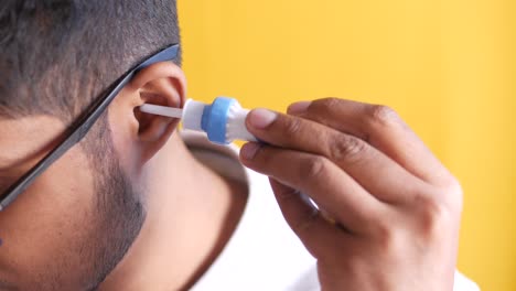 person cleaning their ear with ear drops