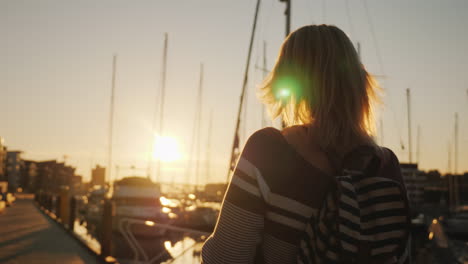 a young woman is using a smartphone walking on a pier at sunset in the background you can see beauti