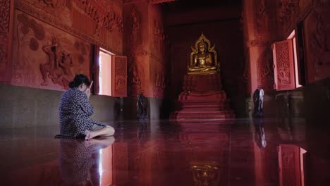 mujer asiática reza en el templo budista sentada en el suelo