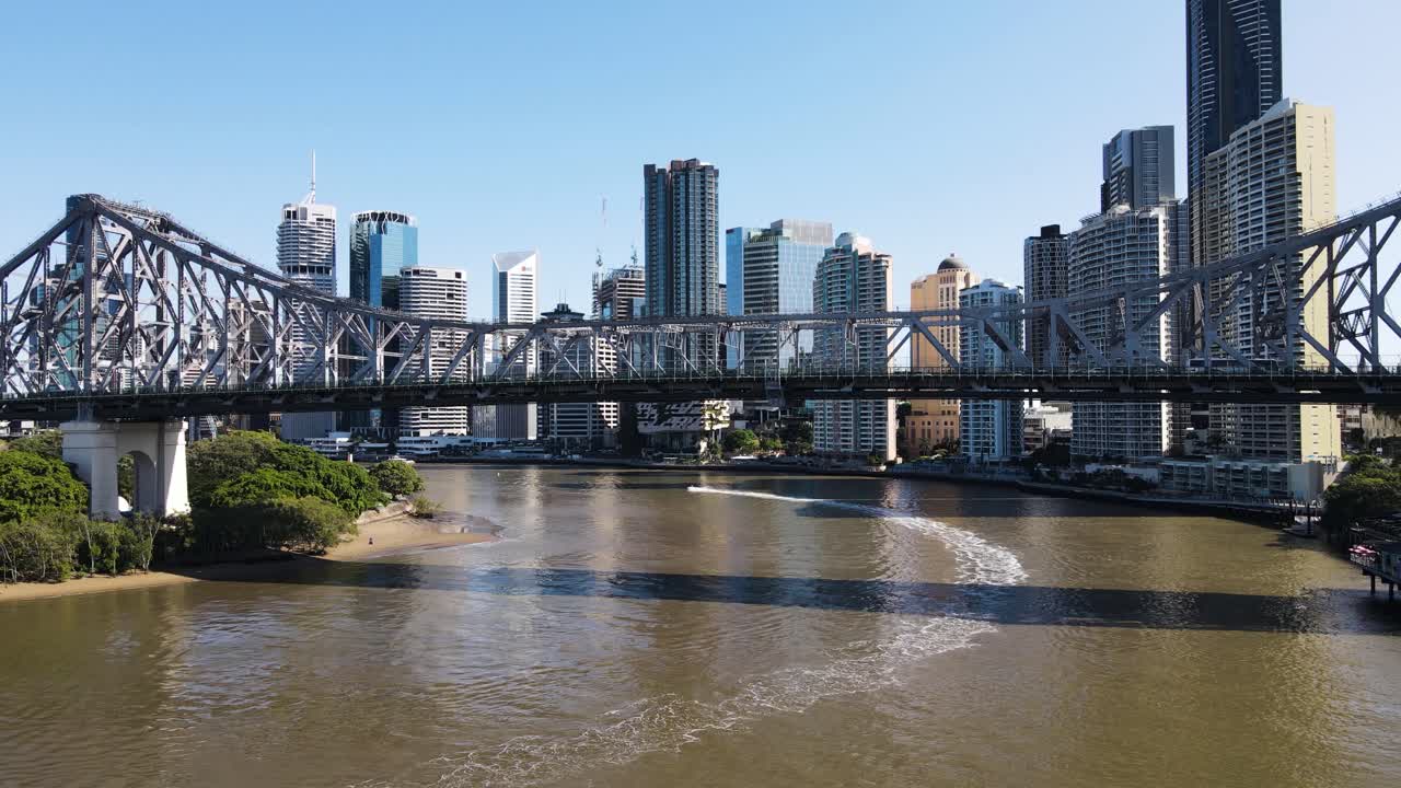 Traveling along the Brisbane River and passing under the icon Story Bridge revealing the towering skyline of Brisbane City. Aerial drone view