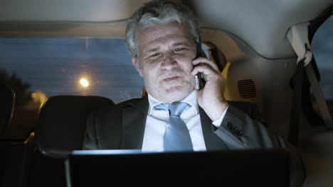 confident man talking on phone while holding laptop on his knees