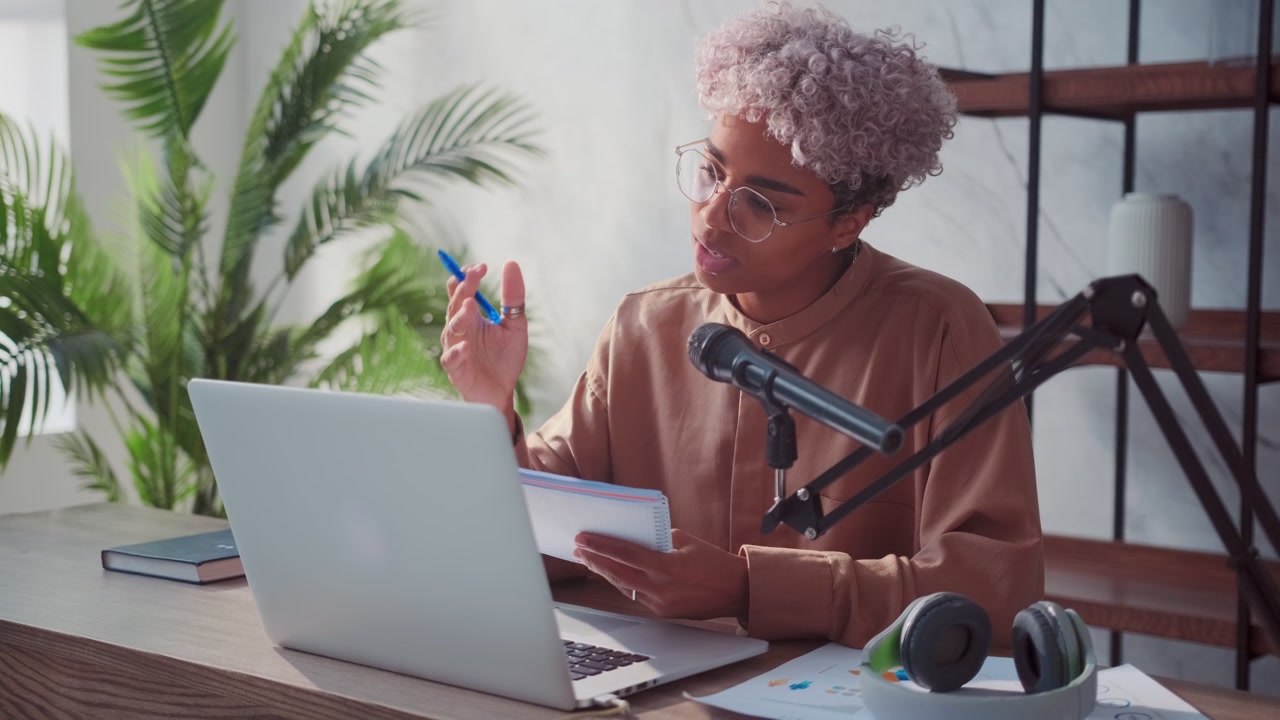 Carried away african american woman talking and making notes in notebook