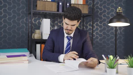 Businessman-examining-and-signing-paperwork-in-his-office.