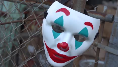 the joker themed clown mask hanging from a chain link fence