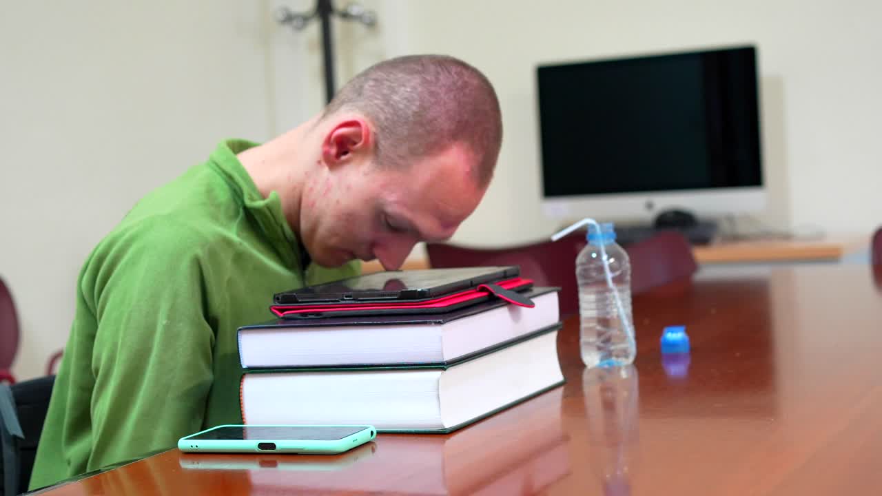 A tired student sleeping on books at a desk