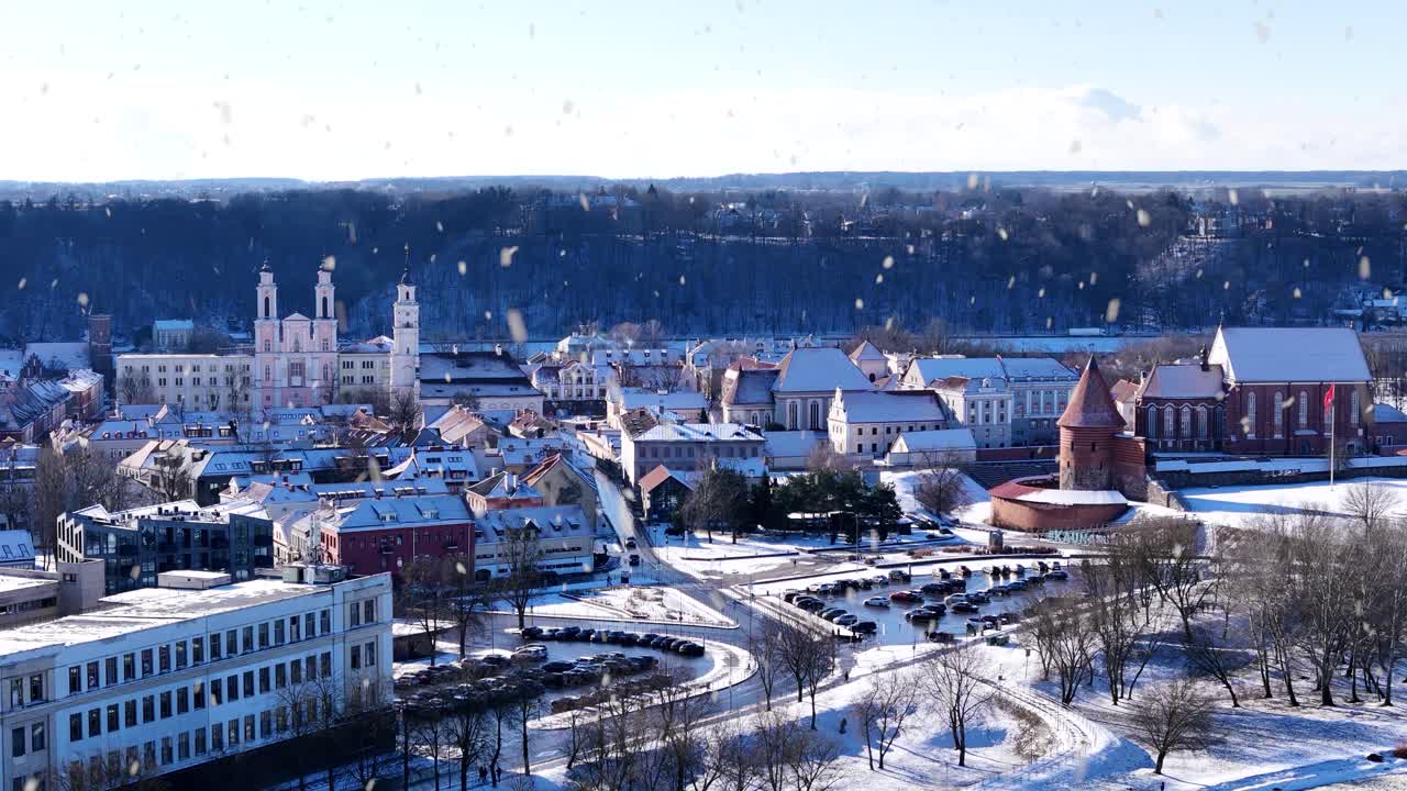 Kaunas oldtown rooftops and castle tower during snowfall, aerial view