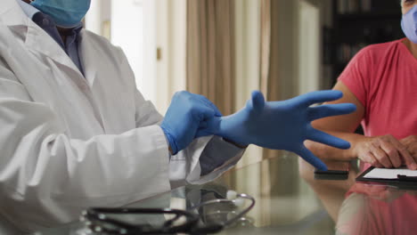 médico de sexo masculino visitando a una mujer de raza mixta que se pone guantes