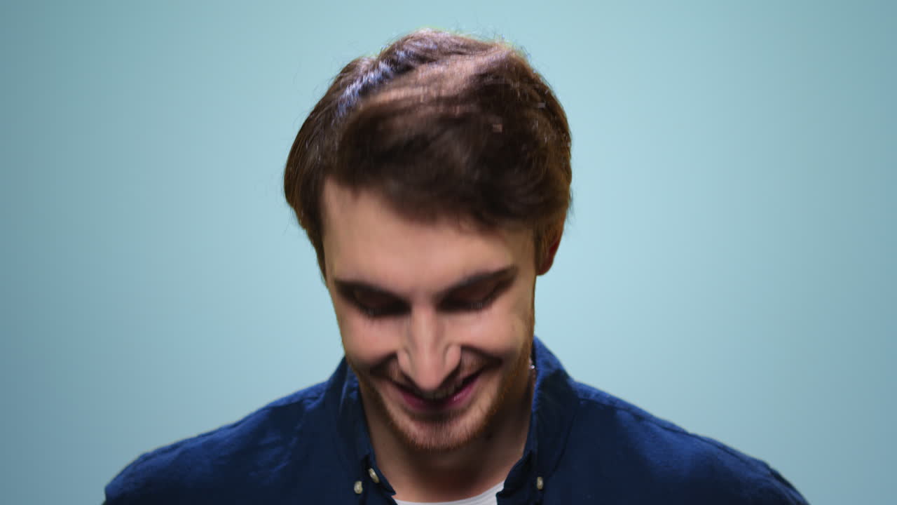 Uomo che annuisce affermativamente in camera. Uomo sorridente su sfondo blu.