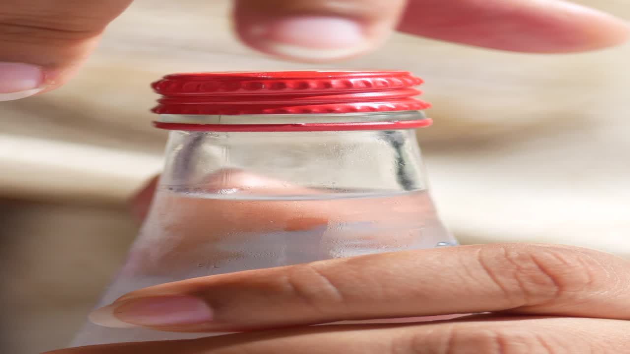 물 한 병 을 열고 있는 손 의 근접적 인 모습