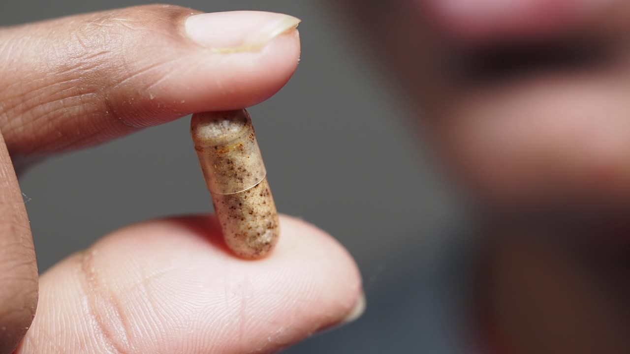Close-up of a hand holding a capsule