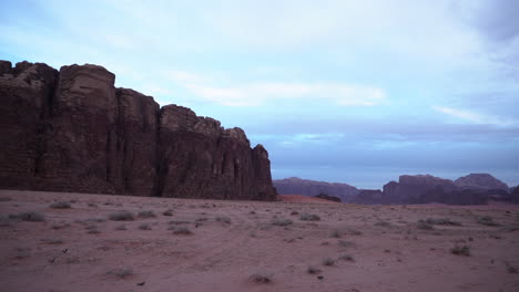 a panoramic shot of wadi rum desert canyon with sand, mountains and white clouds in the background