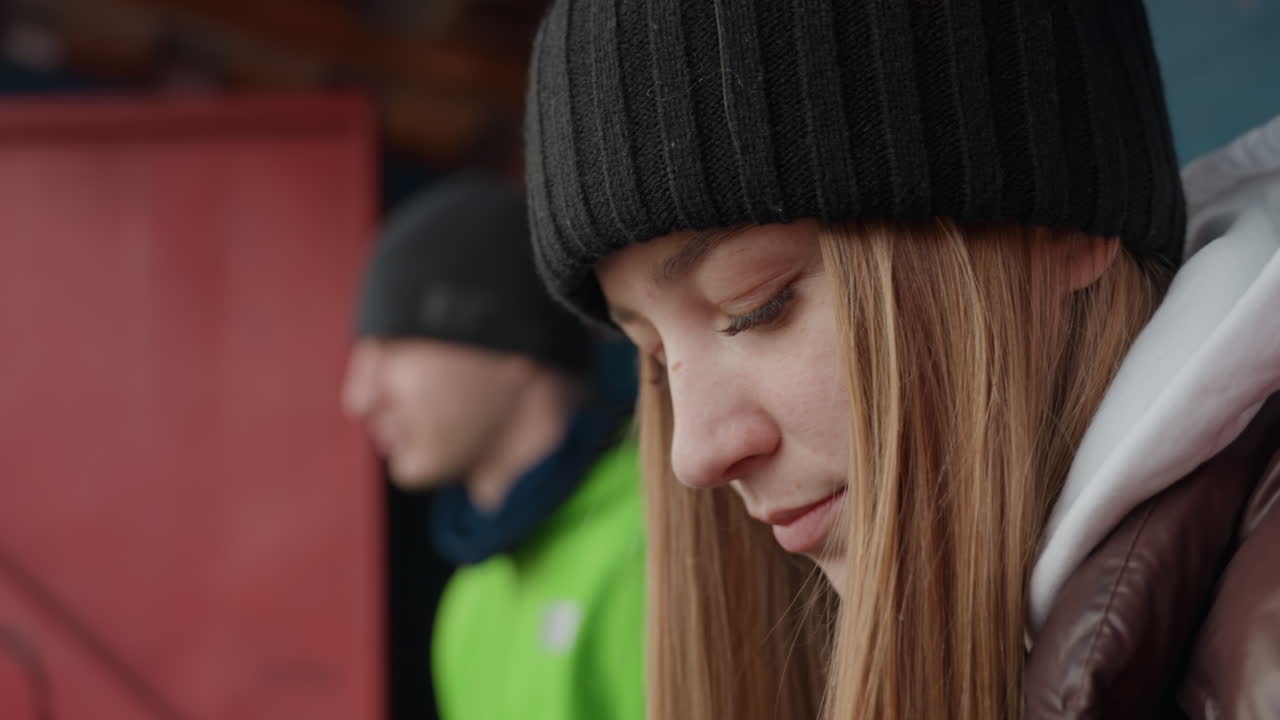 Молодая девушка терпеливо ждет на улице, девочка-подросток с беспокойством отдыхает на скамейке в парке, девушка-подросток спокойно сидит в парке, демонстрируя видимое опасение и тревогу