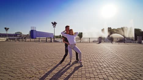 man and woman dancing outdoors. young couple moving synchronously in the street. boy in black and girl in white perform beautiful dance.