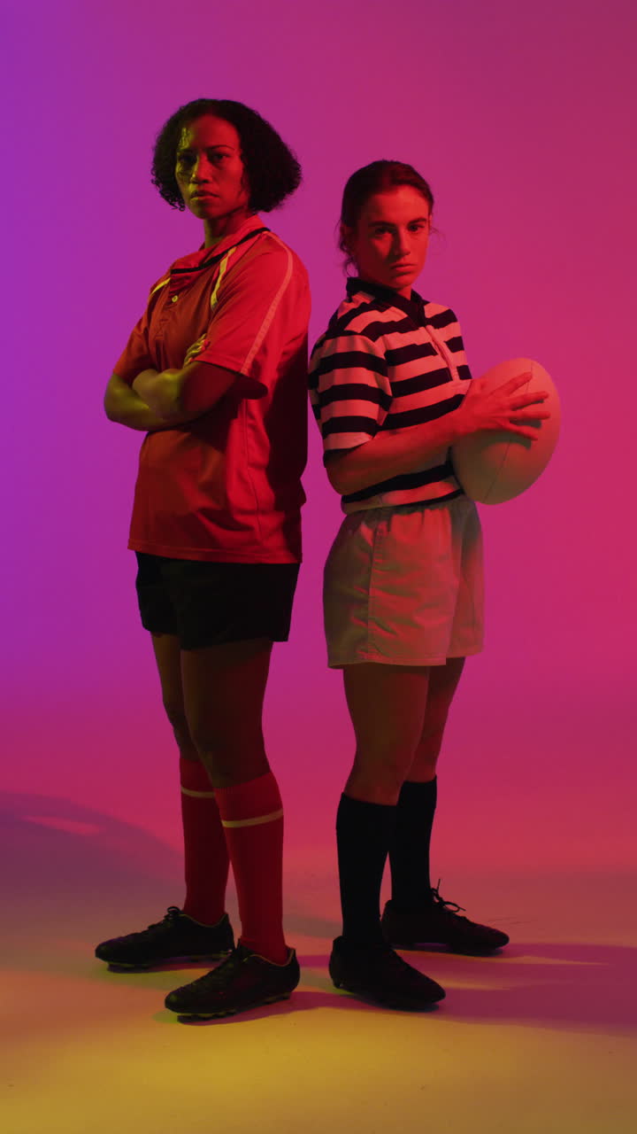 video vertical de retrato de diversas jugadoras de rugby con pelota de rugby sobre iluminación rosa neón