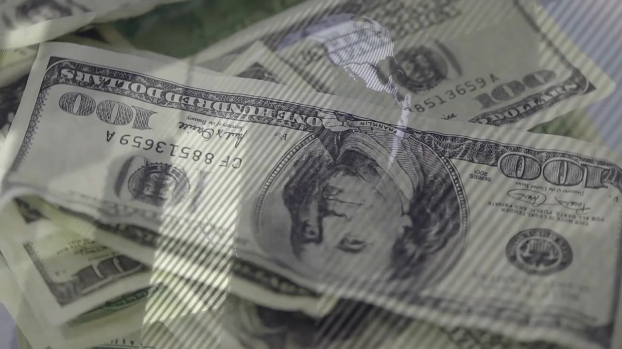 Câmera dolly iniciando movimento, revelando pilha de notas de 100 dólares americanos para mostrar texturas e números de série